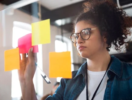 Profissional independente trabalhando em branding pessoal, organizando ideias com post-its em um ambiente moderno e criativo.